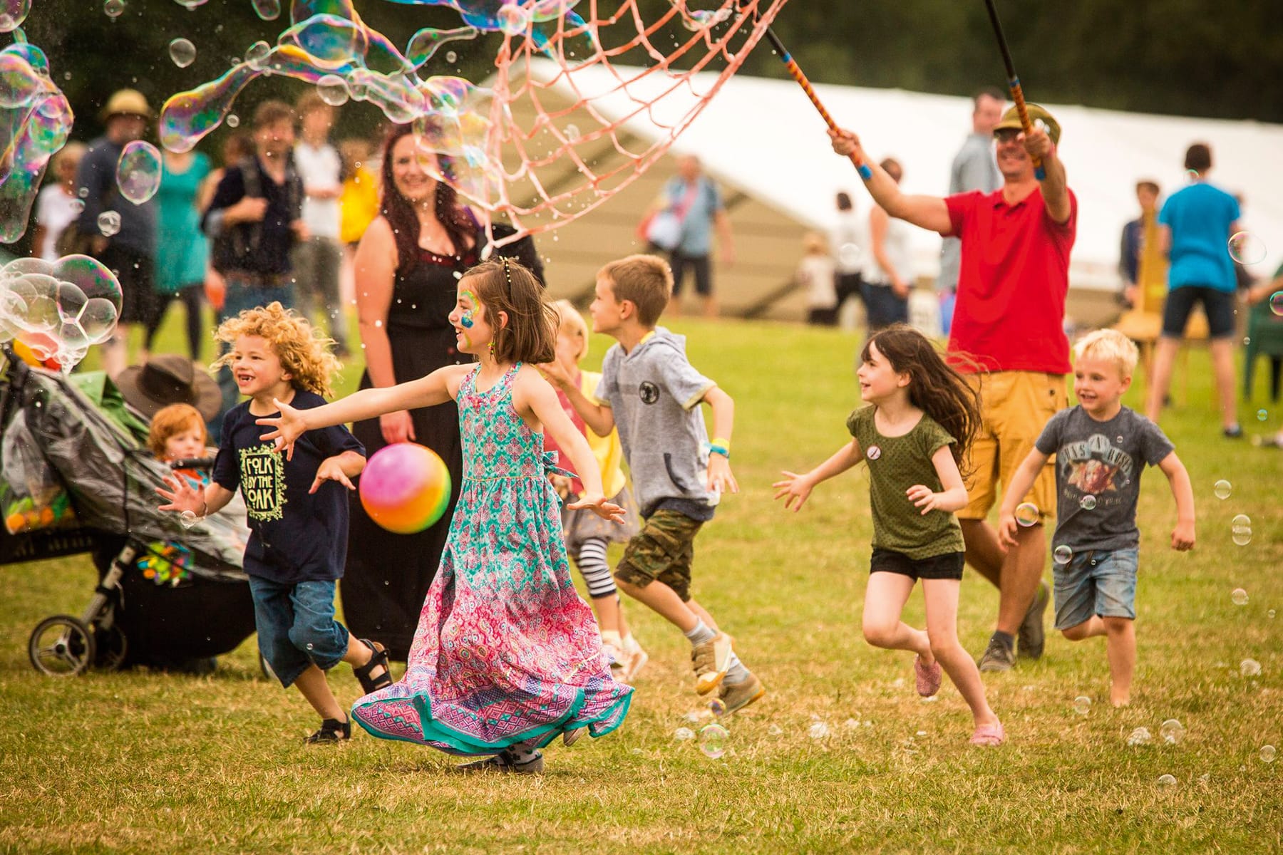 Photograph showing children at a festival running after giant bubbles