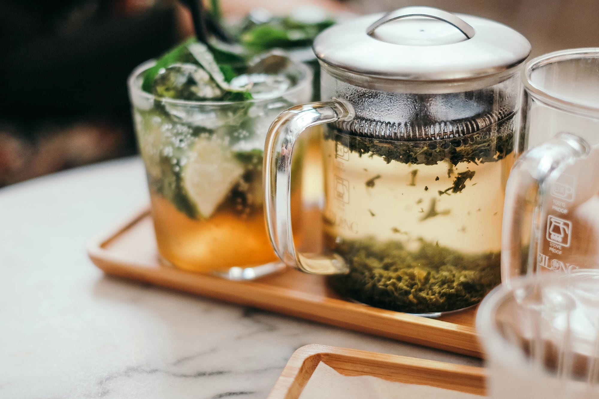 Photograph showing a glass tea strainer with metal lid on a tray