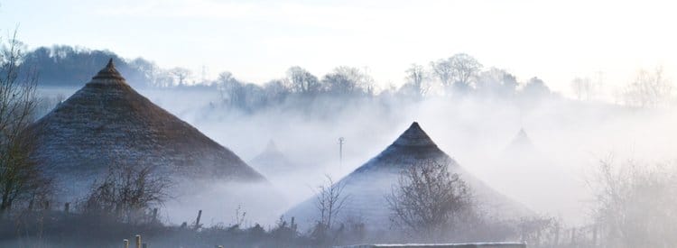 Iron Age sit in a mist against silhouettes of trees. It's winter.