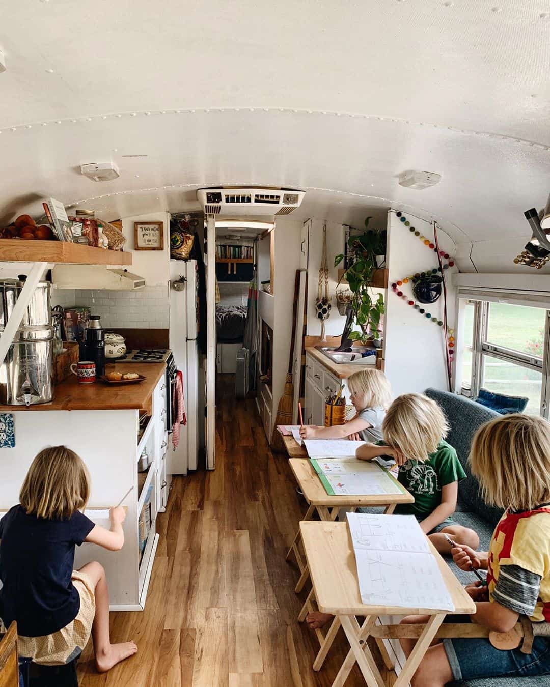 Photograph of a family of four home-educated children sitting at their desks inside a converted schoolbus