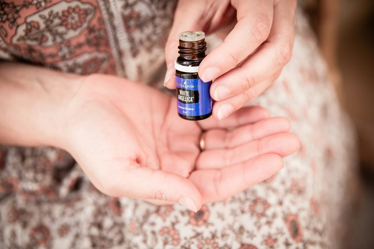 Photograph of hands holding a small bottle of essential oil, over a lap