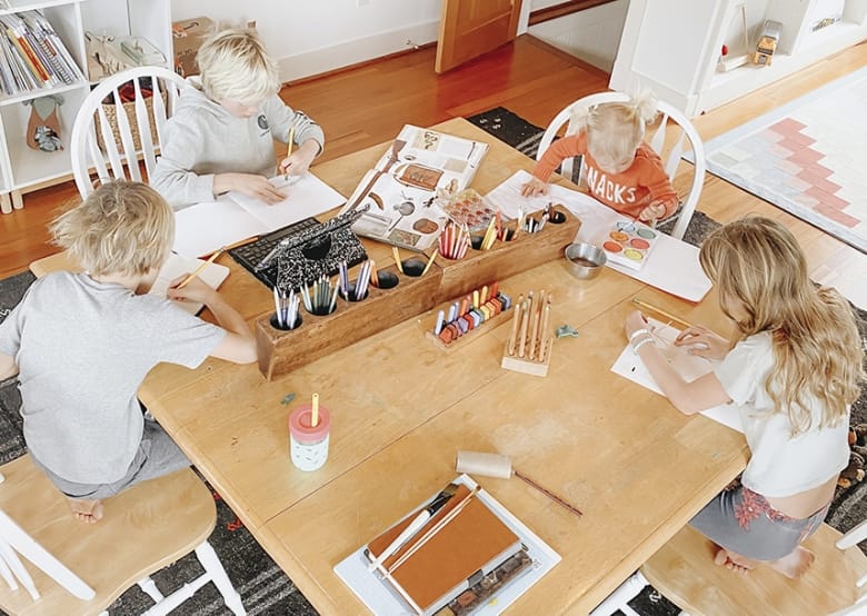 Photograph of four children seated around a square table, each working on his or her own project