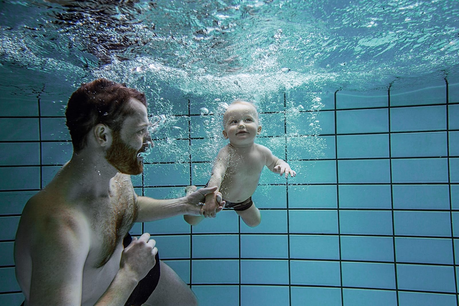 Photograph of a father and his child in a swimming pool, taken underwater