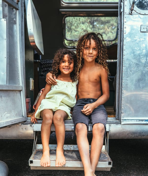 Photograph of two young children in the doorway of an airstream van