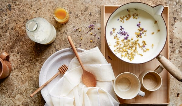Photograph of plant milk in a saucepan with chamomile and lavender flowers