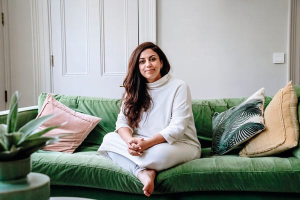 Photograph of a woman looking relaxed and directly at camera on green velvet sofa