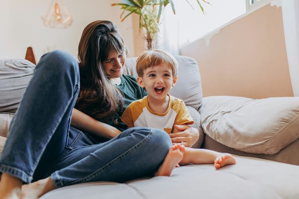 Photograph of a mother and her son curled up together on a sofa