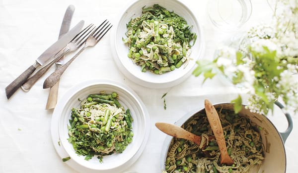 Photograph of two white bowls and a saucepan with pasta and greens inside