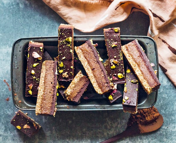 Photograph of a raw vegan chocolate caramel slice piled in a baking tray