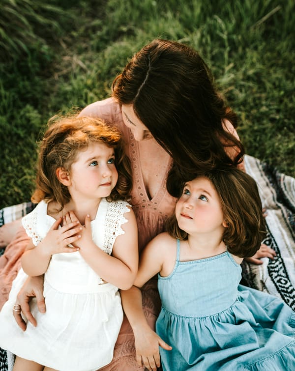 Photograph of a mother with her two daughters on her lap looking up at her