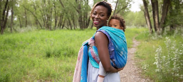 Photograph of a mother with her baby in a colourful woven wrap sling on her back