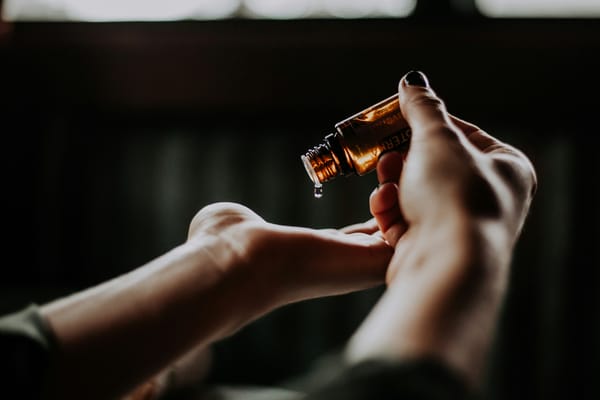 Photograph of a pair of hands with a small bottle of essential oil to be used for back massage
