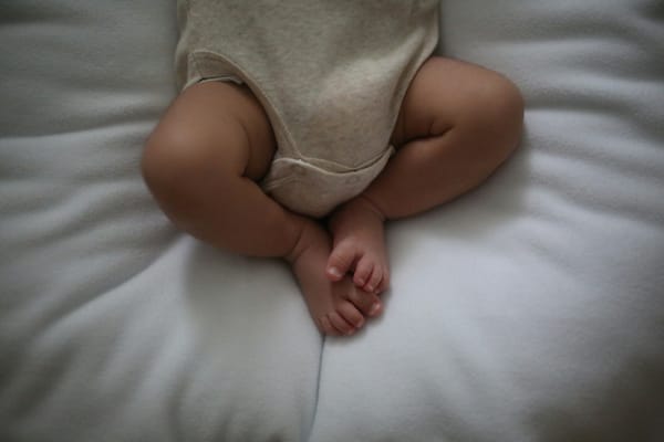 Photo of baby's legs and feet on a mattress