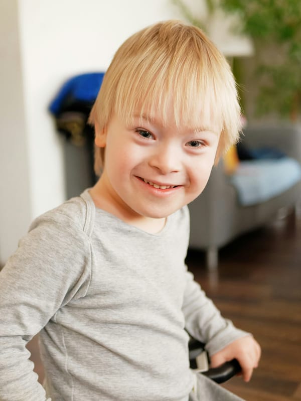 Photograph of a child with Down syndrome smiling at home